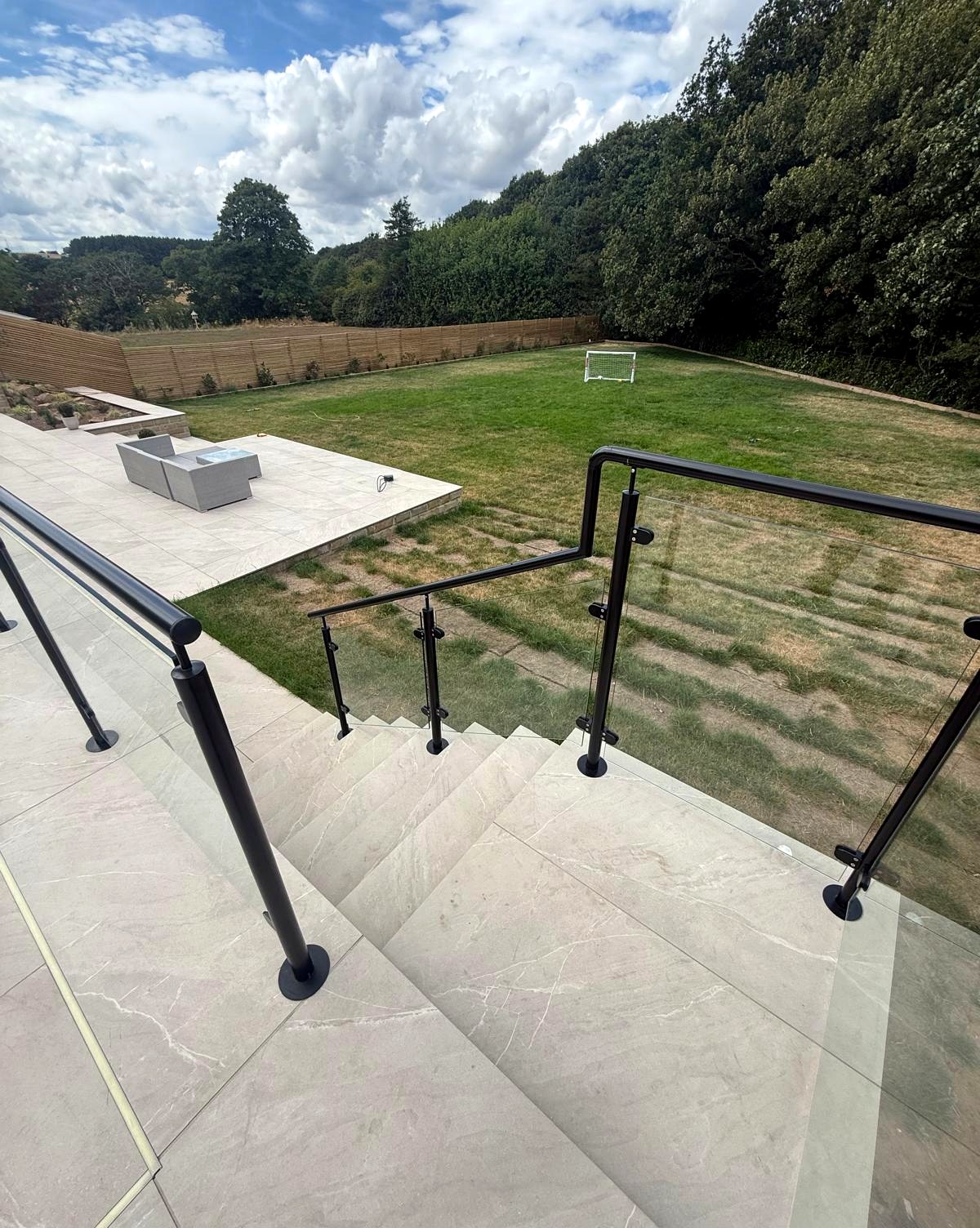 Core-drilled base-fixed glass balustrade and steps on a raised patio overlooking the garden, Sheffield